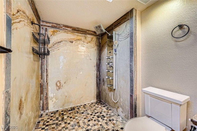 bathroom featuring a textured wall, a stall shower, and toilet