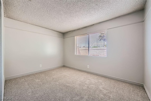 spare room with baseboards, carpet flooring, and a textured ceiling
