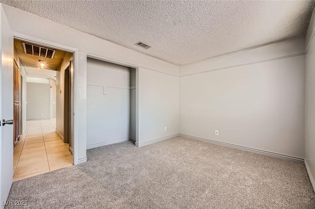 unfurnished bedroom featuring visible vents, a textured ceiling, a closet, and light colored carpet