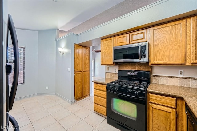 kitchen featuring light tile patterned flooring, baseboards, light countertops, tasteful backsplash, and black appliances