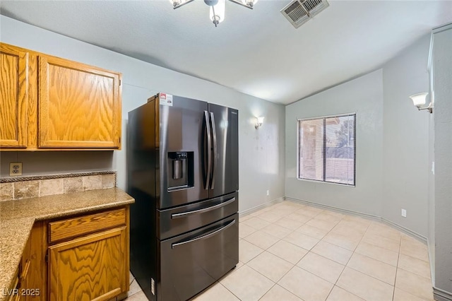 kitchen featuring stainless steel refrigerator with ice dispenser, light countertops, lofted ceiling, and visible vents