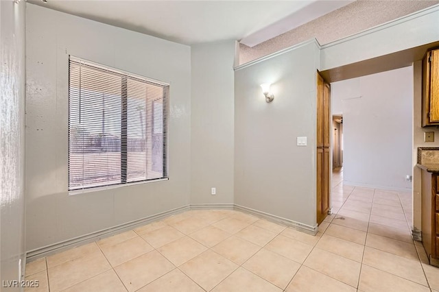 empty room featuring baseboards and light tile patterned floors