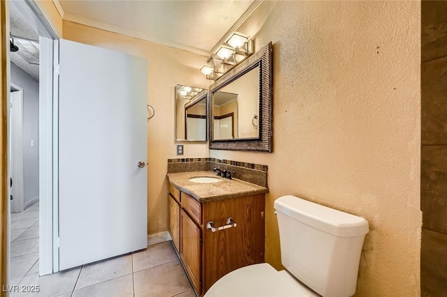 half bathroom with crown molding, vanity, tile patterned flooring, and toilet