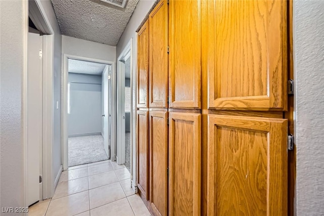 hallway featuring a textured ceiling and light tile patterned floors