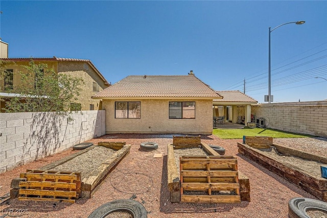 back of property featuring a tile roof, stucco siding, a vegetable garden, a fenced backyard, and a patio area
