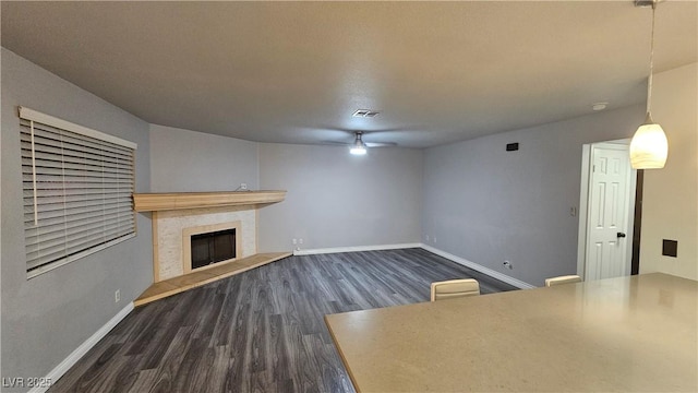 unfurnished living room with dark wood finished floors, baseboards, and a tile fireplace