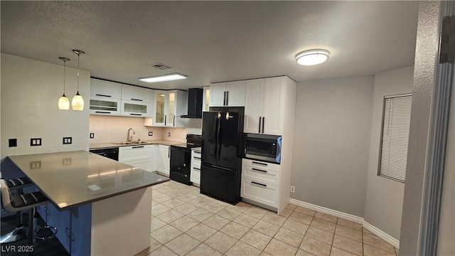 kitchen with black appliances, a peninsula, a kitchen bar, wall chimney exhaust hood, and visible vents