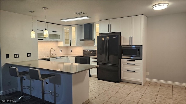 kitchen featuring a sink, black appliances, a peninsula, wall chimney exhaust hood, and visible vents