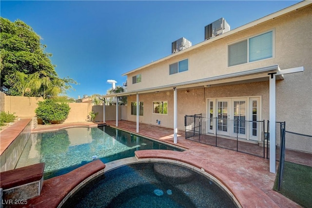 view of swimming pool with french doors, a patio, a pool with connected hot tub, and a fenced backyard