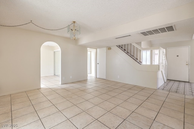 spare room with arched walkways, visible vents, tile patterned flooring, and stairs