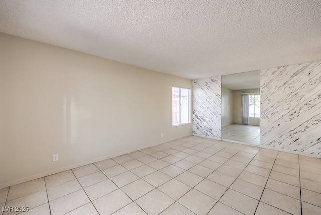 spare room with baseboards, a textured ceiling, wallpapered walls, and light tile patterned floors