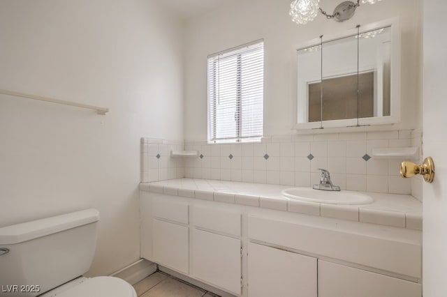 half bathroom featuring toilet, vanity, and decorative backsplash