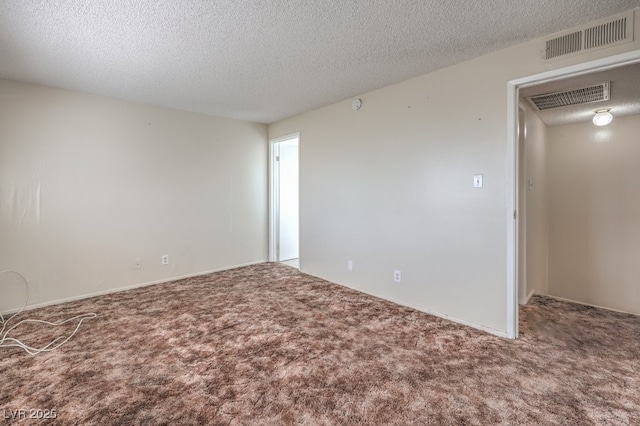 spare room with visible vents, a textured ceiling, and carpet flooring