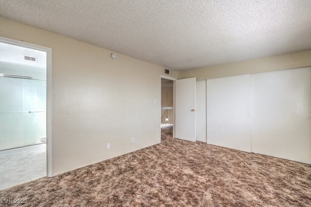carpeted empty room featuring visible vents and a textured ceiling