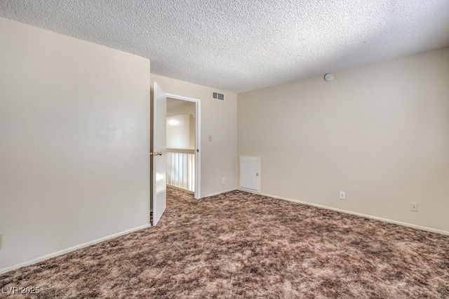 carpeted empty room with baseboards, visible vents, and a textured ceiling
