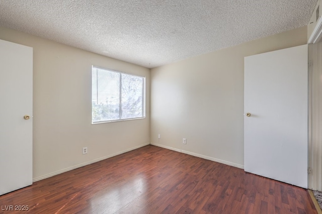 unfurnished room with baseboards, wood finished floors, and a textured ceiling
