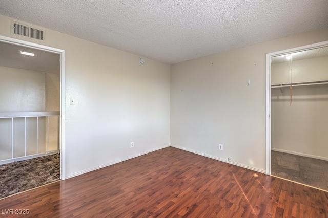unfurnished bedroom featuring a closet, wood finished floors, visible vents, and a textured ceiling
