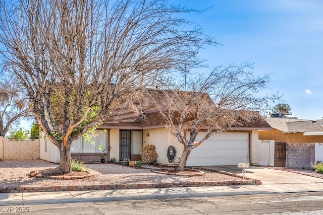 view of front facade featuring an attached garage, concrete driveway, stucco siding, and fence