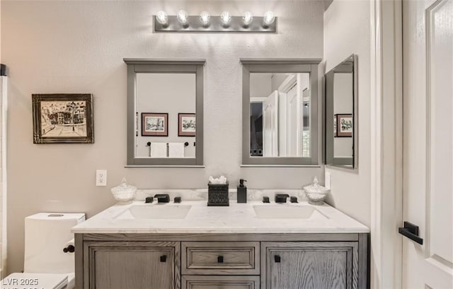 bathroom with double vanity, a sink, and toilet