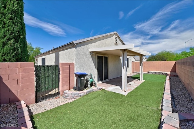 back of house featuring a fenced backyard, a patio, a lawn, and stucco siding