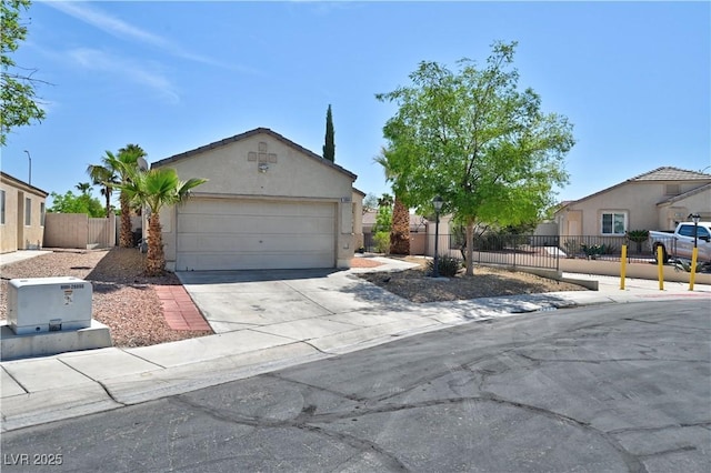 ranch-style house featuring an attached garage, concrete driveway, stucco siding, and fence