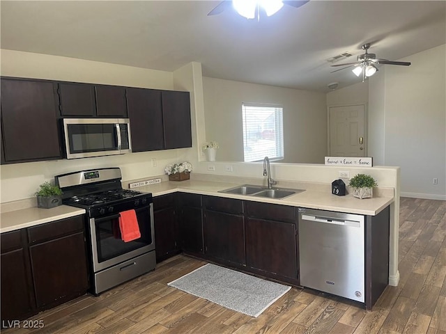 kitchen with stainless steel appliances, a ceiling fan, a sink, dark wood-type flooring, and a peninsula