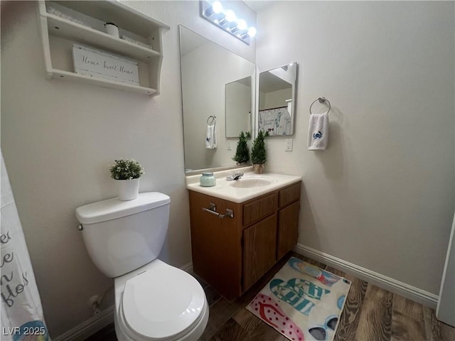 bathroom with toilet, vanity, wood finished floors, and baseboards