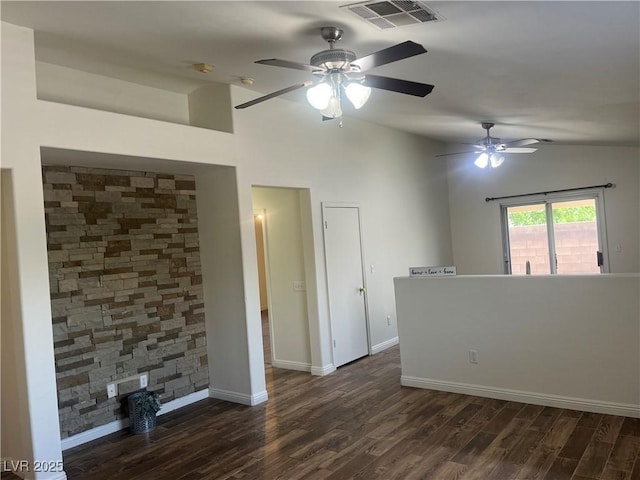empty room featuring dark wood finished floors, ceiling fan, vaulted ceiling, and visible vents