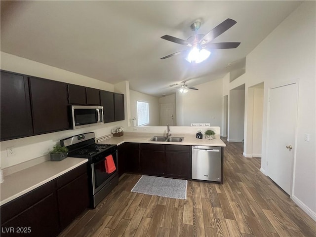 kitchen featuring lofted ceiling, stainless steel appliances, light countertops, a sink, and dark wood-style flooring