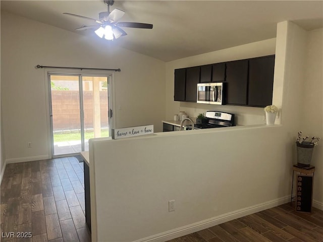 kitchen with lofted ceiling, ceiling fan, dark cabinets, dark wood-type flooring, and appliances with stainless steel finishes