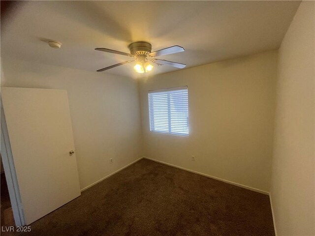 empty room featuring baseboards, a ceiling fan, and dark colored carpet