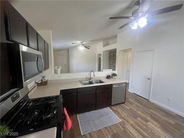 kitchen featuring a ceiling fan, a sink, light wood-style flooring, stainless steel appliances, and light countertops