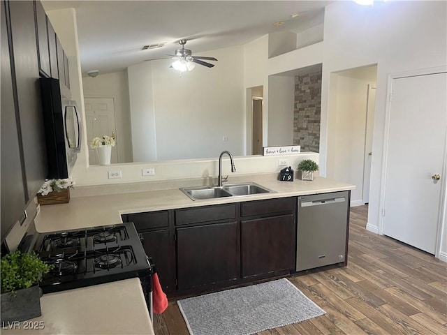 kitchen featuring stainless steel appliances, a sink, a ceiling fan, wood finished floors, and light countertops