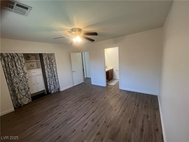 unfurnished bedroom with dark wood finished floors, baseboards, visible vents, a ceiling fan, and connected bathroom