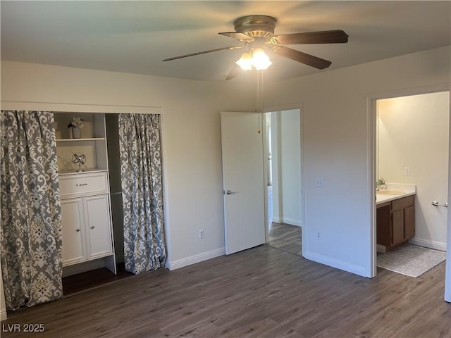 unfurnished bedroom with dark wood-type flooring, ensuite bath, baseboards, and ceiling fan