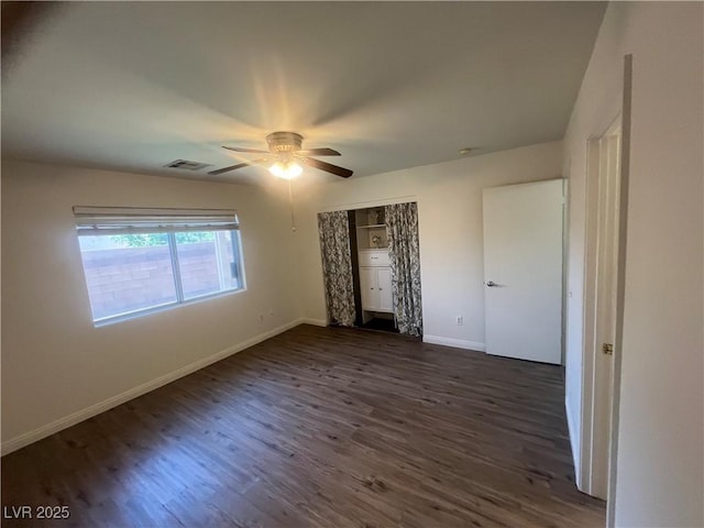 unfurnished bedroom with a ceiling fan, a closet, baseboards, dark wood-style flooring, and visible vents