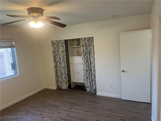 unfurnished bedroom featuring baseboards, a ceiling fan, dark wood-style floors, and a closet