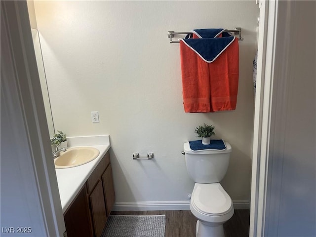 bathroom with wood finished floors, baseboards, vanity, and toilet