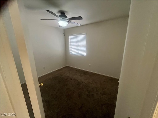 spare room with baseboards, a ceiling fan, and dark colored carpet