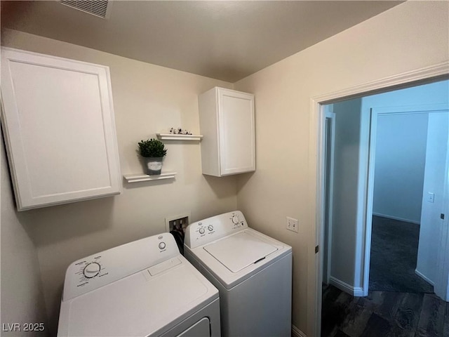 clothes washing area featuring washing machine and dryer, visible vents, and cabinet space
