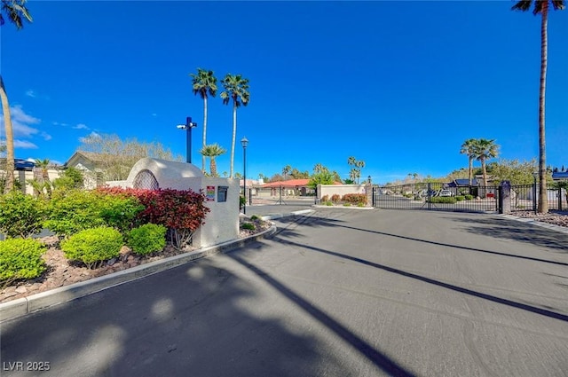 view of street with street lights, a gated entry, a gate, and curbs