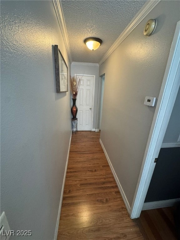 corridor with ornamental molding, a textured ceiling, baseboards, and dark wood-type flooring