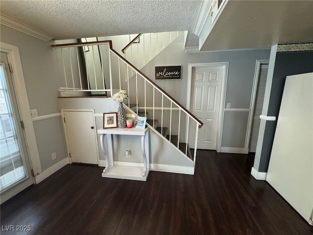 staircase with crown molding, a textured ceiling, baseboards, and wood finished floors