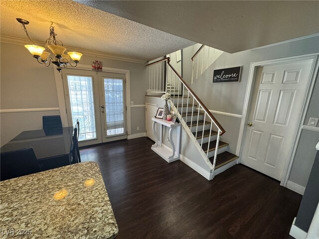 dining room featuring french doors, a notable chandelier, dark wood finished floors, ornamental molding, and stairs