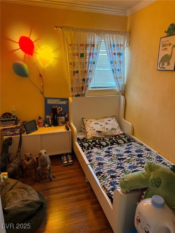 bedroom with wood finished floors and ornamental molding
