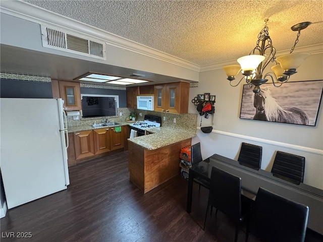 kitchen with a textured ceiling, white appliances, a sink, a peninsula, and brown cabinets