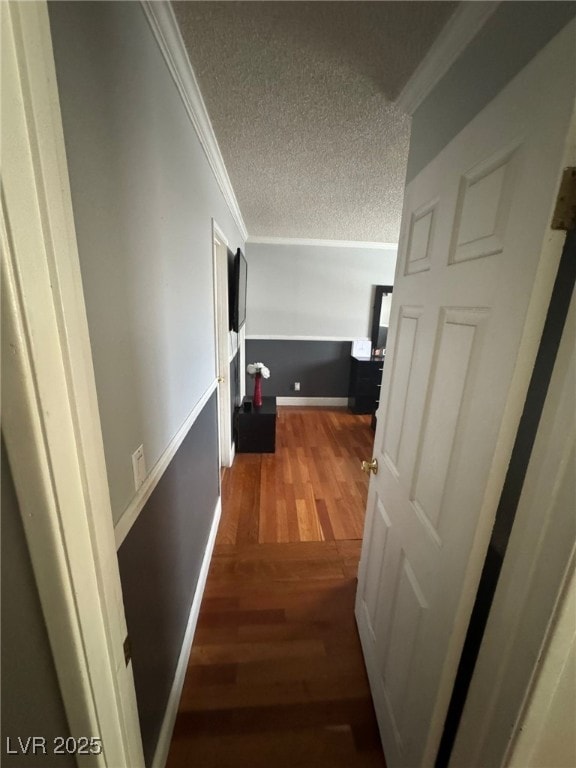hall with baseboards, crown molding, a textured ceiling, and wood finished floors
