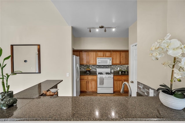 10550 W Alexander Rd Unit 2103, Las Vegas, NV 89129 - kitchen featuring white appliances, decorative backsplash, brown cabinetry, and a peninsula
