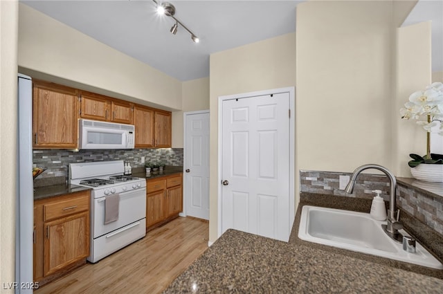 10550 W Alexander Rd Unit 2103, Las Vegas, NV 89129 - kitchen with white appliances, dark countertops, tasteful backsplash, light wood-style flooring, and brown cabinetry