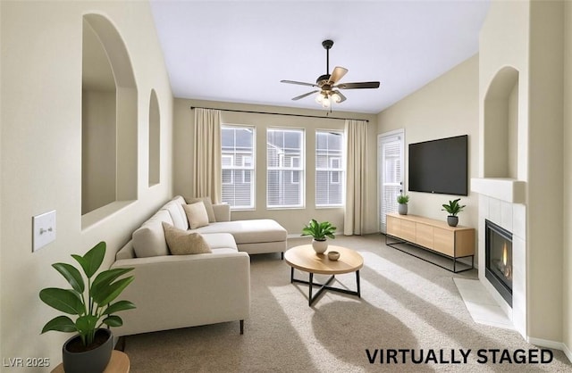 living area with a fireplace, baseboards, a ceiling fan, and light colored carpet